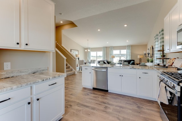 kitchen with lofted ceiling, white cabinets, light wood-type flooring, appliances with stainless steel finishes, and kitchen peninsula