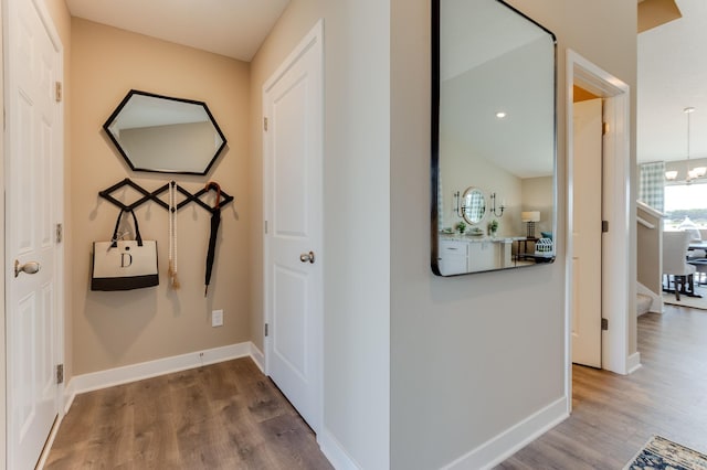 hall with wood-type flooring and an inviting chandelier