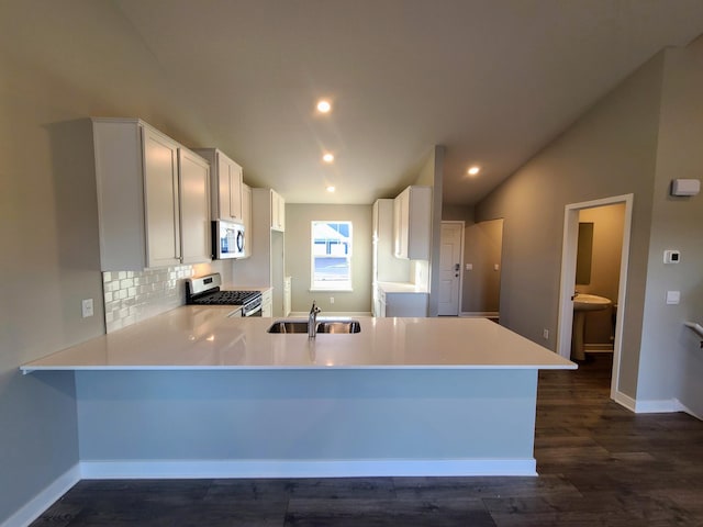 kitchen with sink, stainless steel appliances, dark wood-type flooring, backsplash, and kitchen peninsula