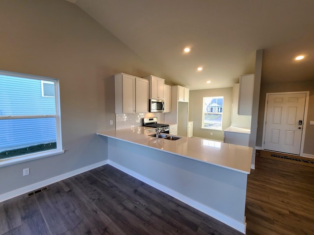 kitchen featuring kitchen peninsula, dark hardwood / wood-style flooring, white cabinetry, and lofted ceiling