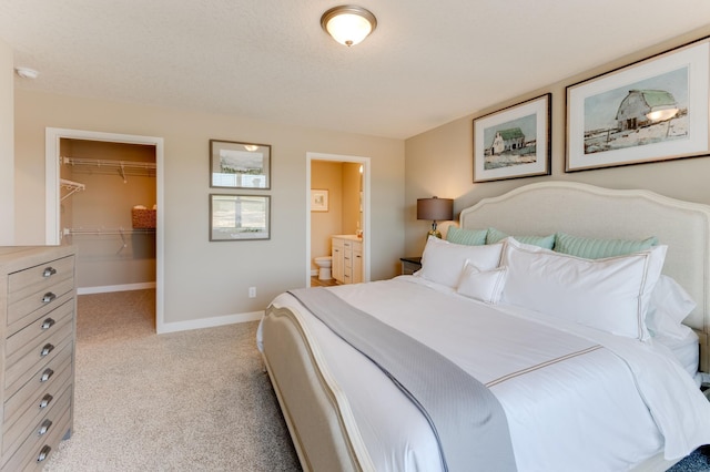 bedroom featuring light carpet, ensuite bathroom, a spacious closet, and a closet