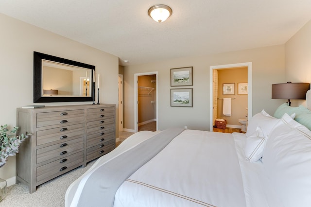 carpeted bedroom featuring connected bathroom, a walk in closet, and a closet