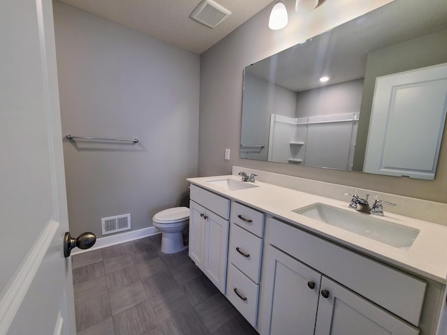 bathroom featuring vanity, toilet, and walk in shower