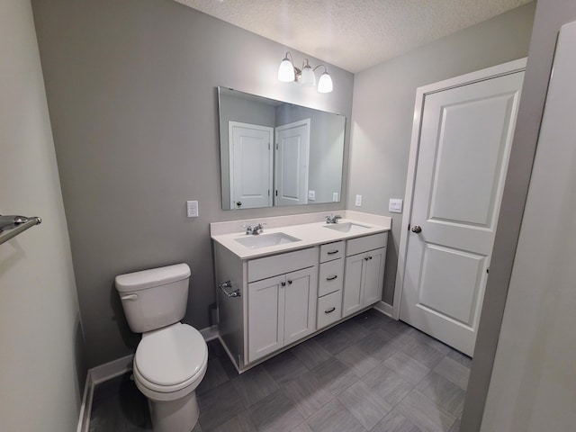 bathroom featuring vanity, a textured ceiling, and toilet