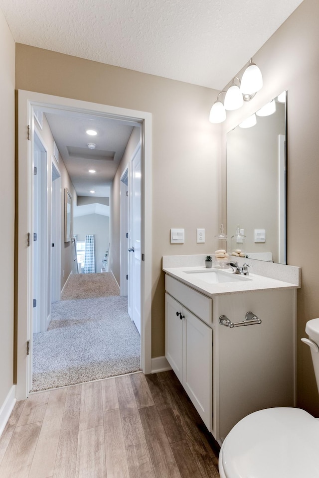 bathroom with a textured ceiling, vanity, hardwood / wood-style flooring, and toilet