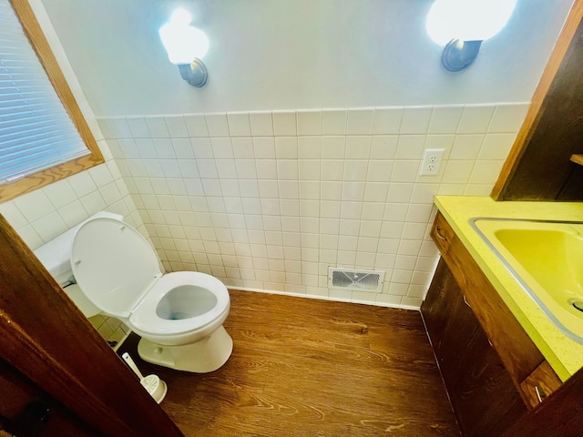 bathroom featuring tile walls, hardwood / wood-style floors, vanity, and toilet