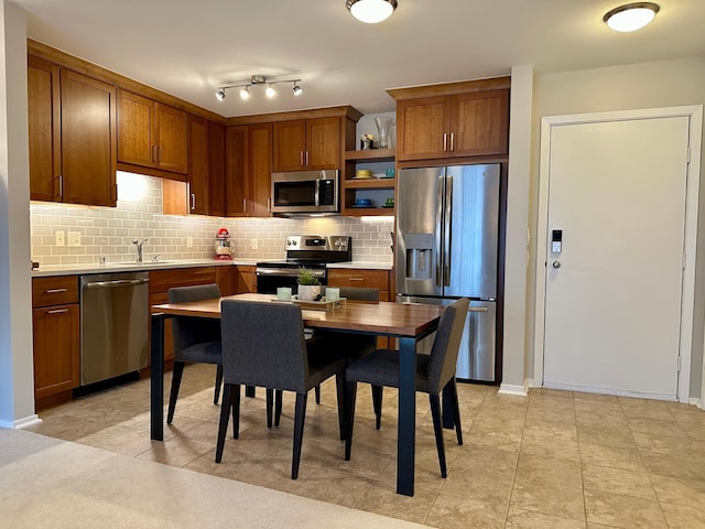 kitchen with light tile patterned flooring, backsplash, and appliances with stainless steel finishes