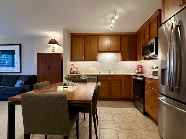 kitchen with sink, light tile patterned floors, stainless steel appliances, and tasteful backsplash