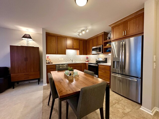 kitchen featuring light tile patterned floors, backsplash, stainless steel appliances, and sink