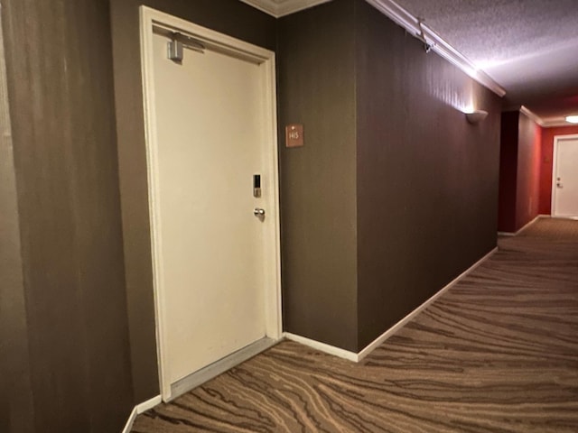 hall featuring dark colored carpet, a textured ceiling, and crown molding