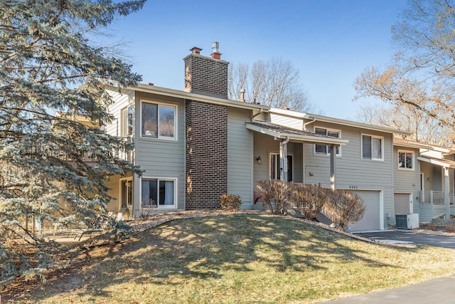 view of front of home with central AC unit, a garage, and a front lawn