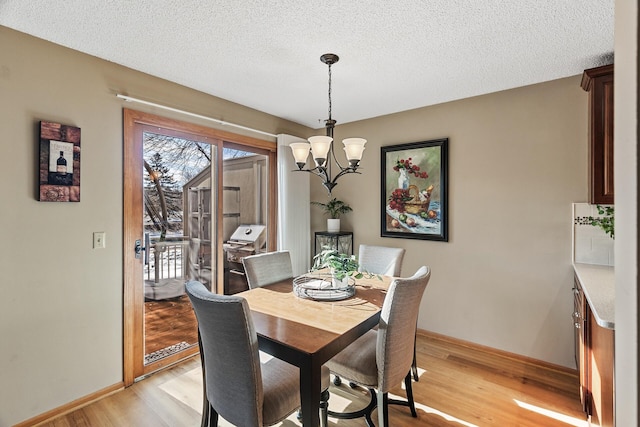 dining space featuring an inviting chandelier, a textured ceiling, and light wood-type flooring