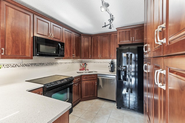 kitchen with sink, light tile patterned floors, tasteful backsplash, black appliances, and a textured ceiling