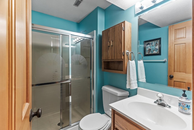 bathroom with vanity, toilet, a shower with shower door, and a textured ceiling