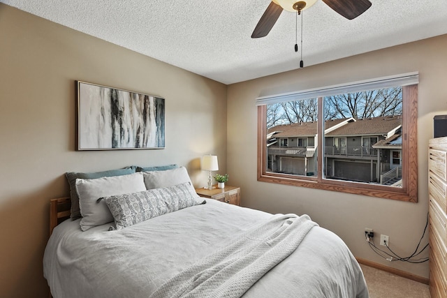 carpeted bedroom featuring ceiling fan and a textured ceiling