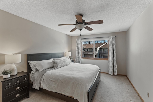 bedroom featuring ceiling fan, light colored carpet, and a textured ceiling