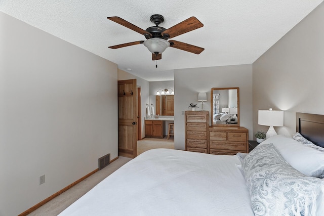 carpeted bedroom with ensuite bath, a textured ceiling, and ceiling fan