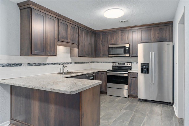 kitchen featuring sink, a textured ceiling, dark brown cabinets, kitchen peninsula, and stainless steel appliances