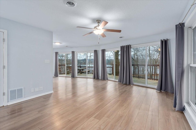 unfurnished room with a textured ceiling, light wood-type flooring, and ceiling fan