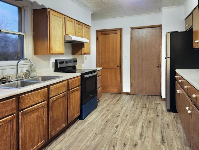 kitchen featuring electric range, light wood-type flooring, sink, and stainless steel refrigerator