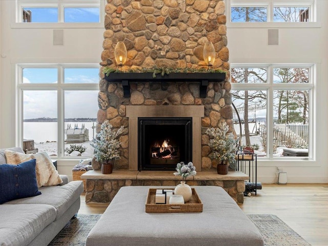 living room featuring hardwood / wood-style flooring, a high ceiling, a water view, and a fireplace