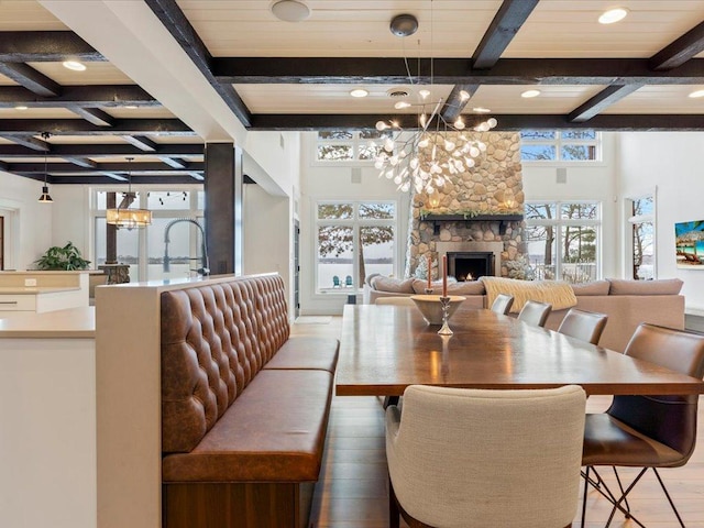 dining space featuring a fireplace, beamed ceiling, coffered ceiling, and a chandelier