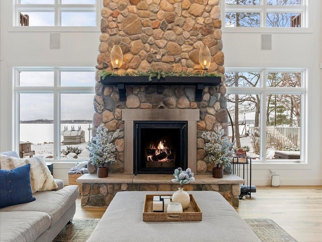 living room with a high ceiling, hardwood / wood-style floors, and a stone fireplace