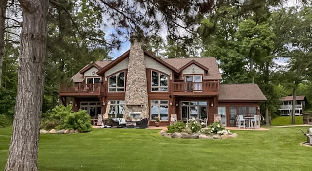 rear view of property featuring a balcony, a yard, and french doors