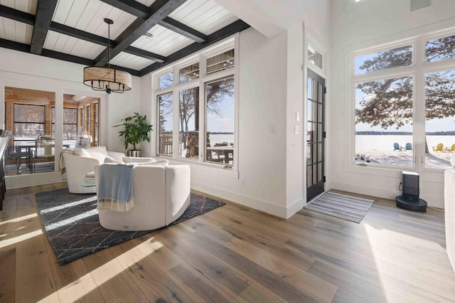 interior space with coffered ceiling, hardwood / wood-style flooring, beam ceiling, a chandelier, and a water view