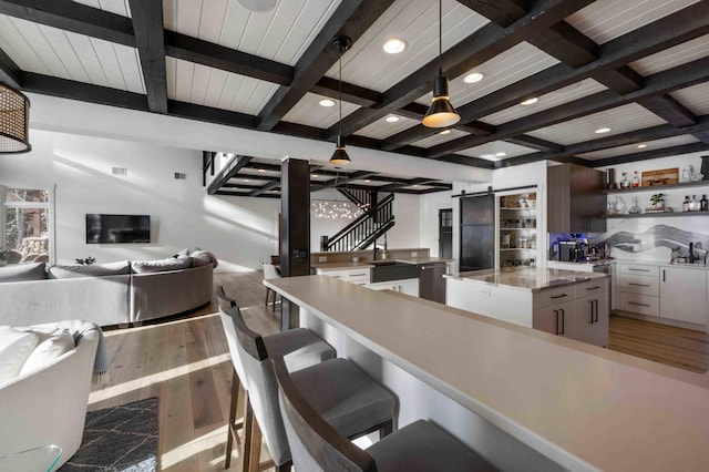 kitchen featuring decorative light fixtures, a spacious island, white cabinets, and beamed ceiling