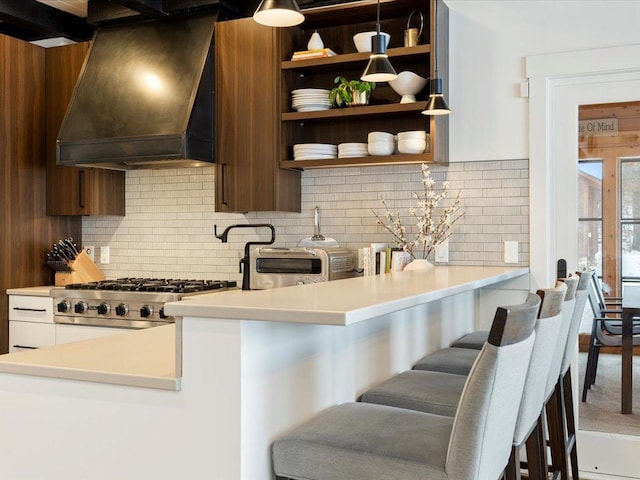 kitchen with white cabinets, range, custom exhaust hood, decorative backsplash, and kitchen peninsula