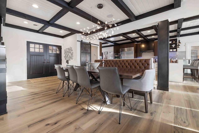 dining space featuring light hardwood / wood-style floors, beam ceiling, coffered ceiling, and a barn door