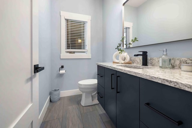 bathroom with toilet, vanity, and wood-type flooring