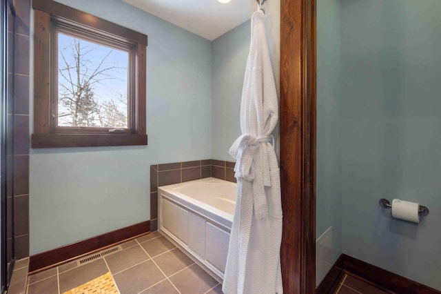 bathroom with a tub to relax in and tile patterned floors