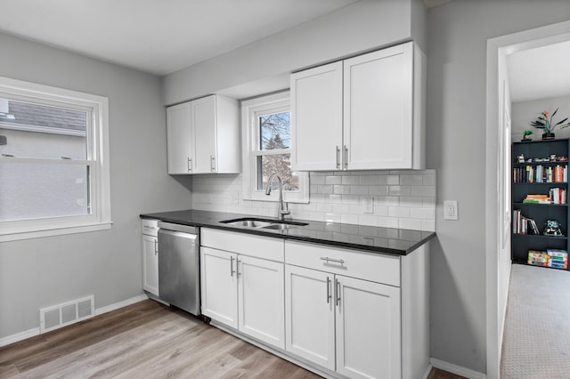 kitchen featuring backsplash, light hardwood / wood-style floors, stainless steel dishwasher, sink, and white cabinetry