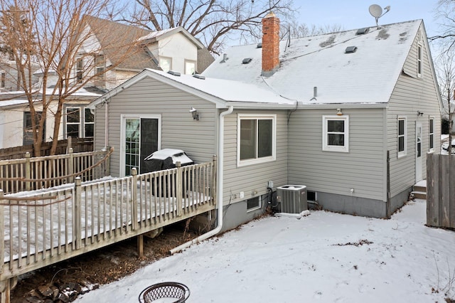 snow covered house with a deck and cooling unit