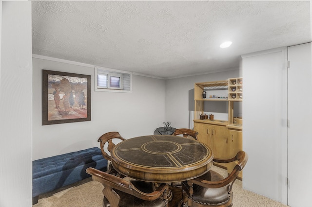 carpeted dining room with ornamental molding and a textured ceiling