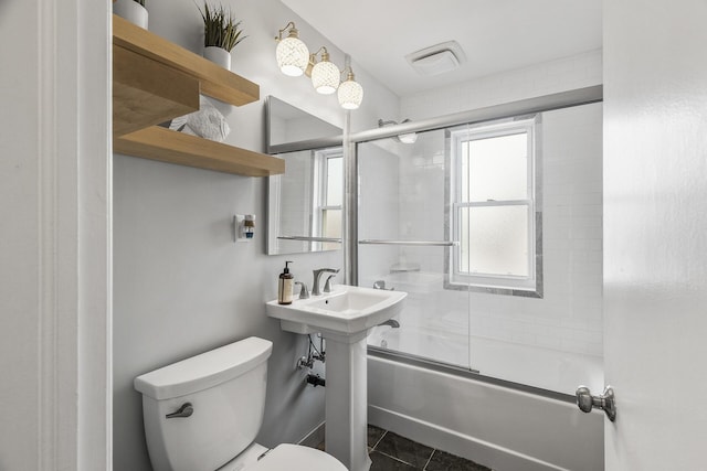 bathroom featuring tile patterned flooring, visible vents, toilet, and combined bath / shower with glass door