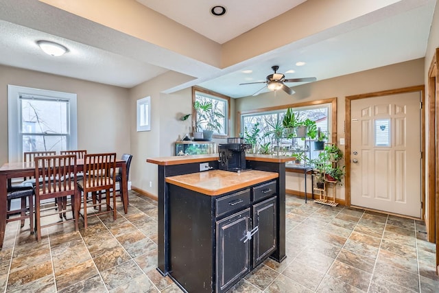 kitchen with wooden counters, a kitchen island, and ceiling fan