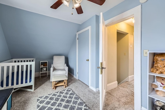 carpeted bedroom with a crib, vaulted ceiling, and ceiling fan