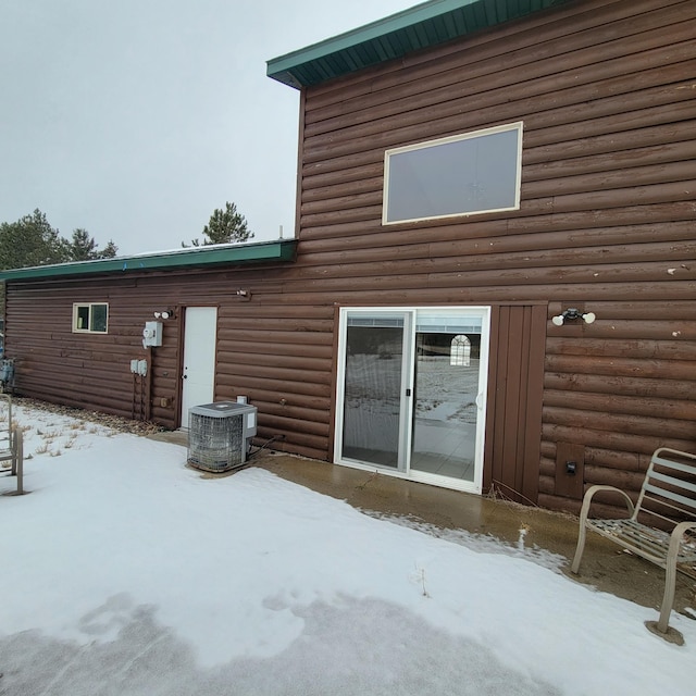 snow covered rear of property featuring central AC