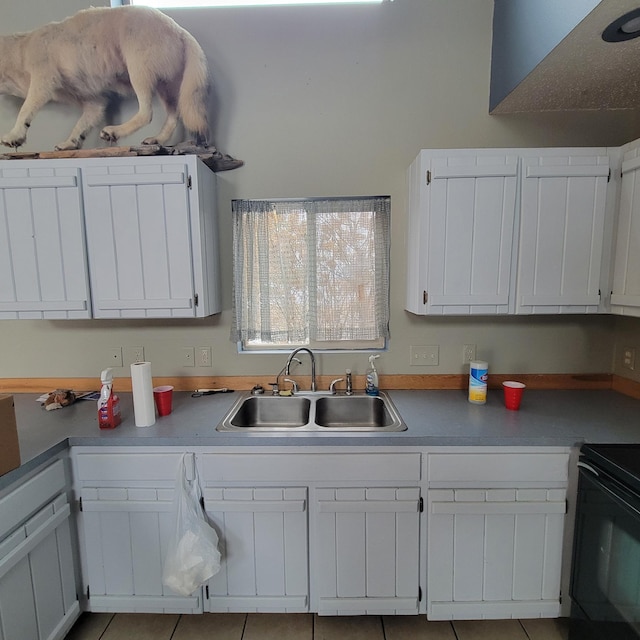 kitchen featuring electric range, sink, white cabinets, and light tile patterned floors