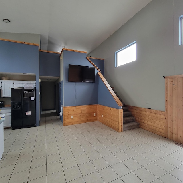 unfurnished living room featuring wood walls and light tile patterned floors