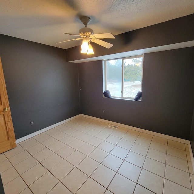 unfurnished room with ceiling fan, light tile patterned floors, and a textured ceiling