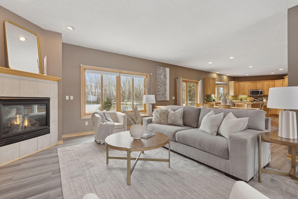 living room with a tile fireplace, light hardwood / wood-style floors, and a textured ceiling