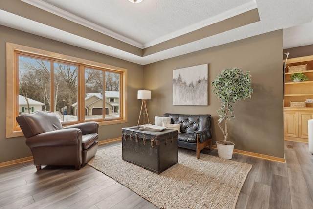 living room with wood-type flooring, crown molding, a textured ceiling, and a tray ceiling