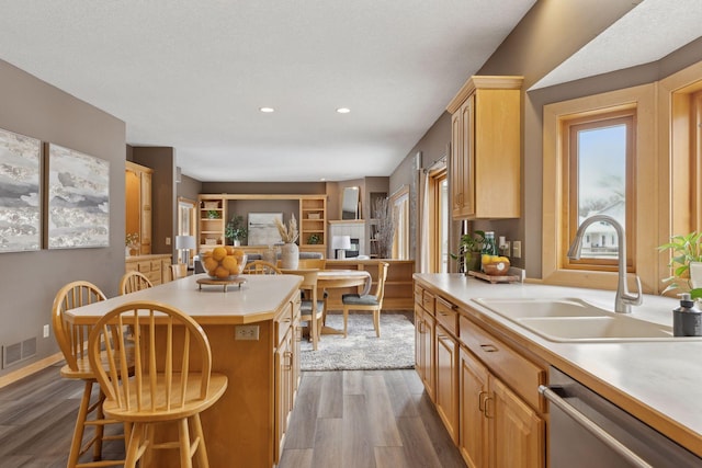 kitchen featuring sink, stainless steel dishwasher, a center island, and light brown cabinets