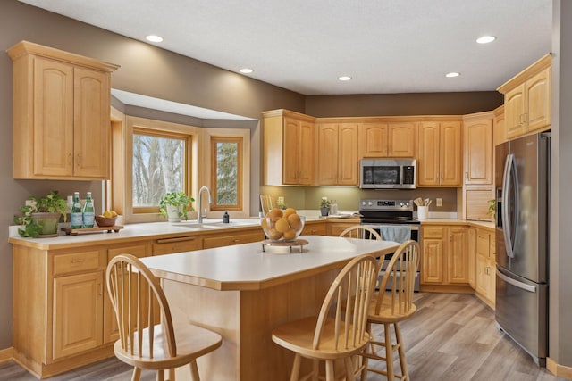 kitchen with a breakfast bar, sink, a center island, light wood-type flooring, and stainless steel appliances