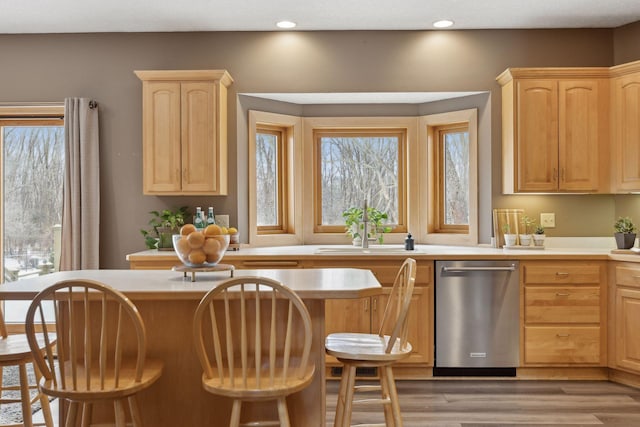 kitchen featuring dishwasher, a breakfast bar, and light brown cabinets