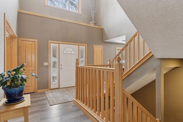 entryway featuring a textured ceiling, a high ceiling, and light wood-type flooring